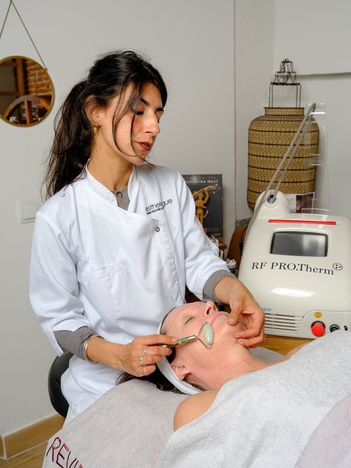 Esteticista realizando un masaje facial con rodillo de jade tras la radiofrecuencia en la clínica Marta Grazia de Madrid